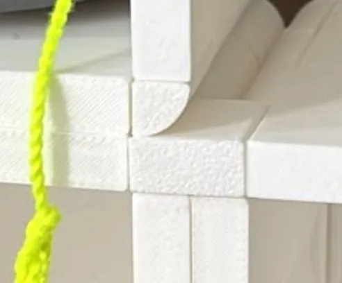 Close-up of a white ThrowGRID corner connector joining four cube edges