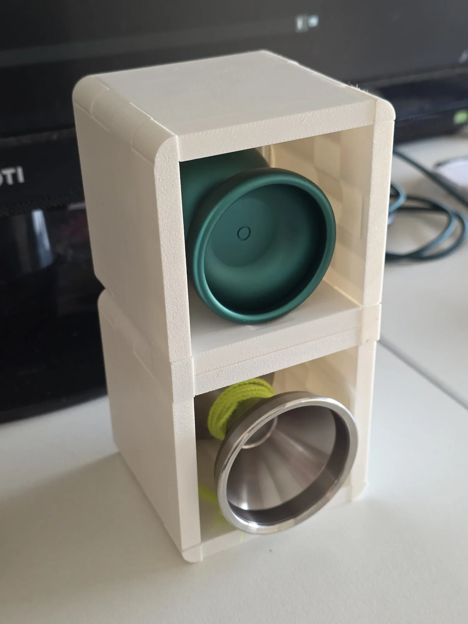 Two white ThrowGRID cubes stacked vertically holding a teal and a steel yo-yo